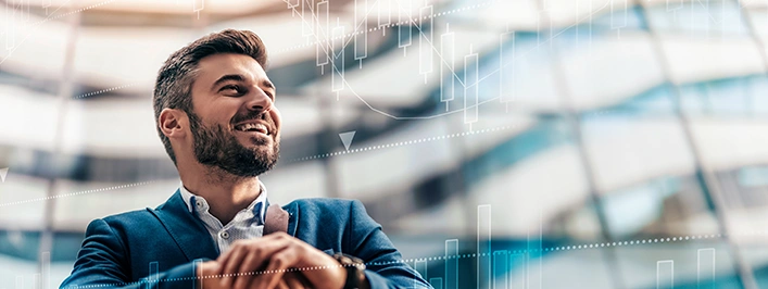 Man sitting in a large glass building looking in the distance while smiling